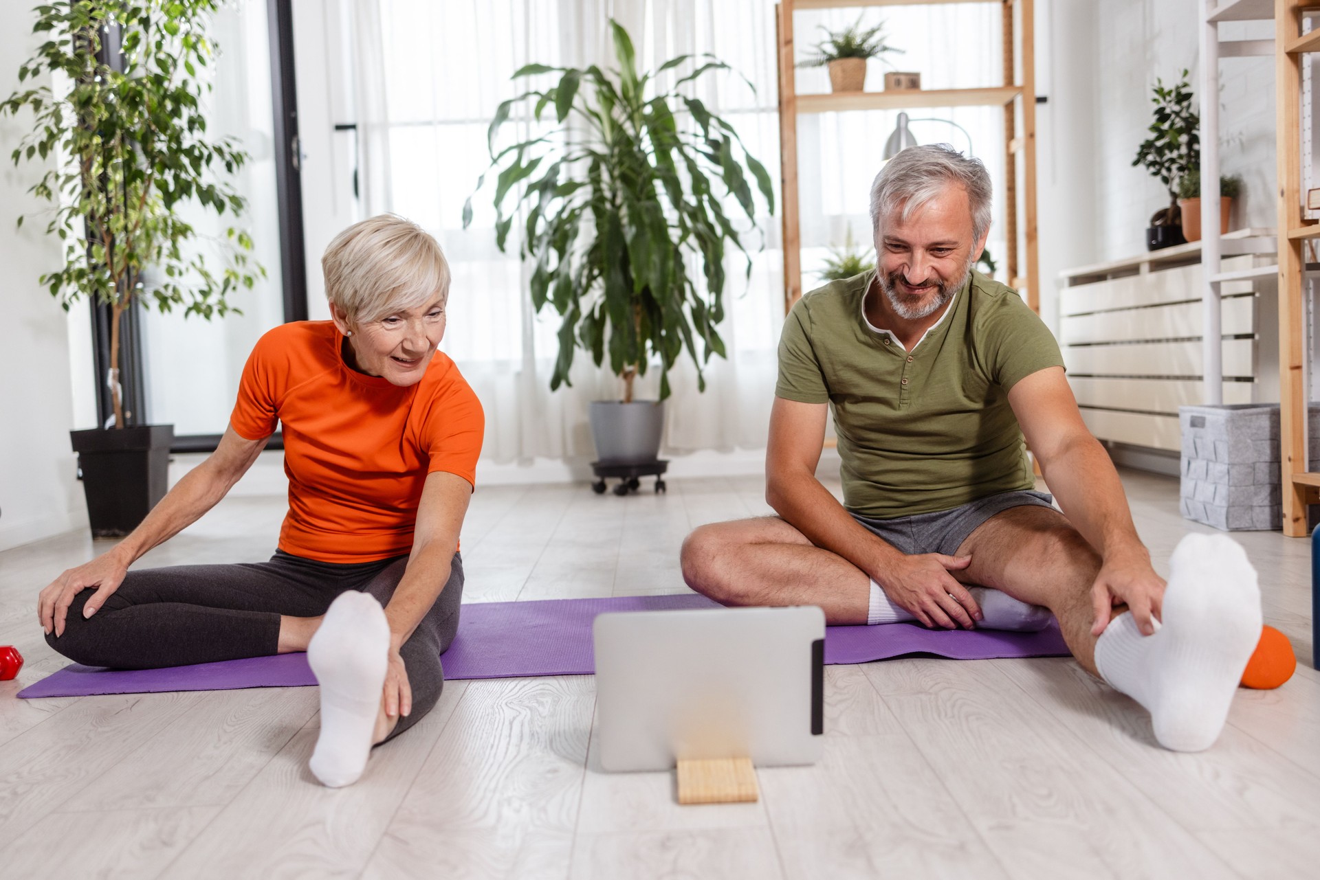 Photo of a heterosexual couple attentively following an online yoga class