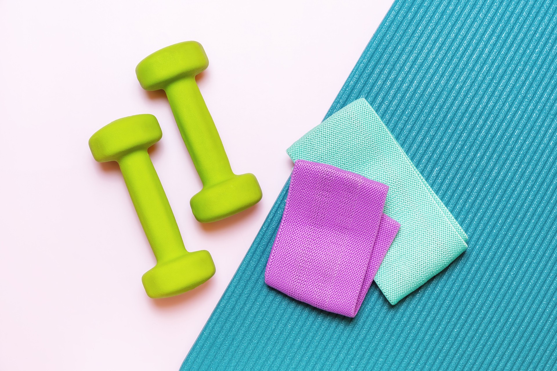 Green dumbbells, purple and mint resistance bands, and a teal yoga mat