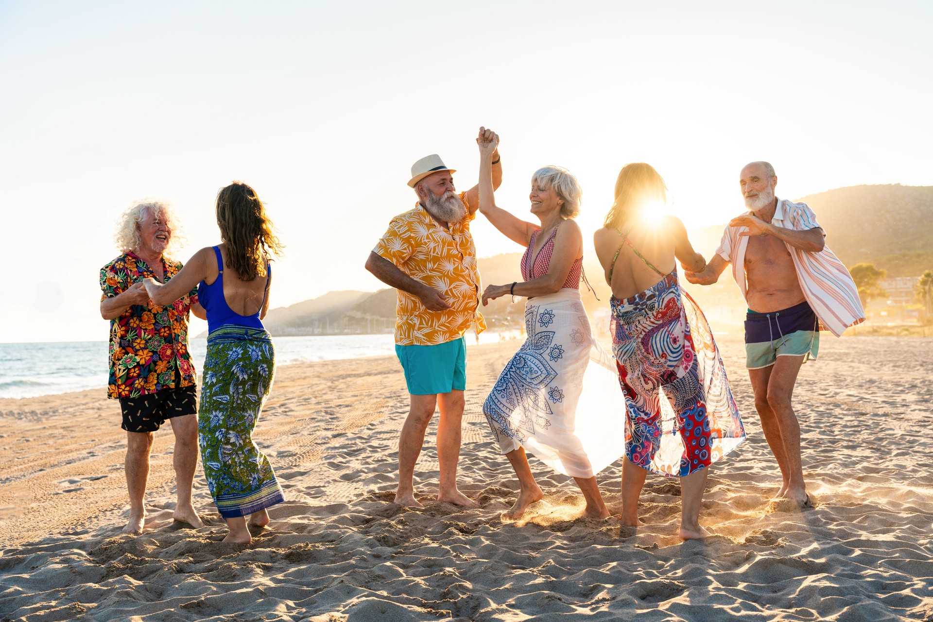 Happy group of senior friends bonding at the beach during summertime